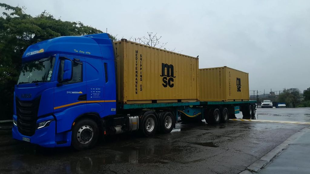 Spectrans truck carrying two shipping containers on a flatbed trailer